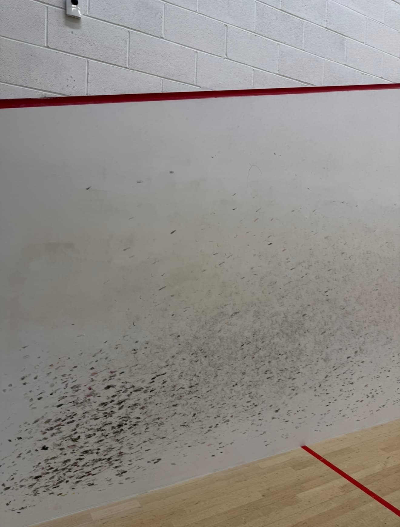 Marked and worn squash court side wall before refinishing